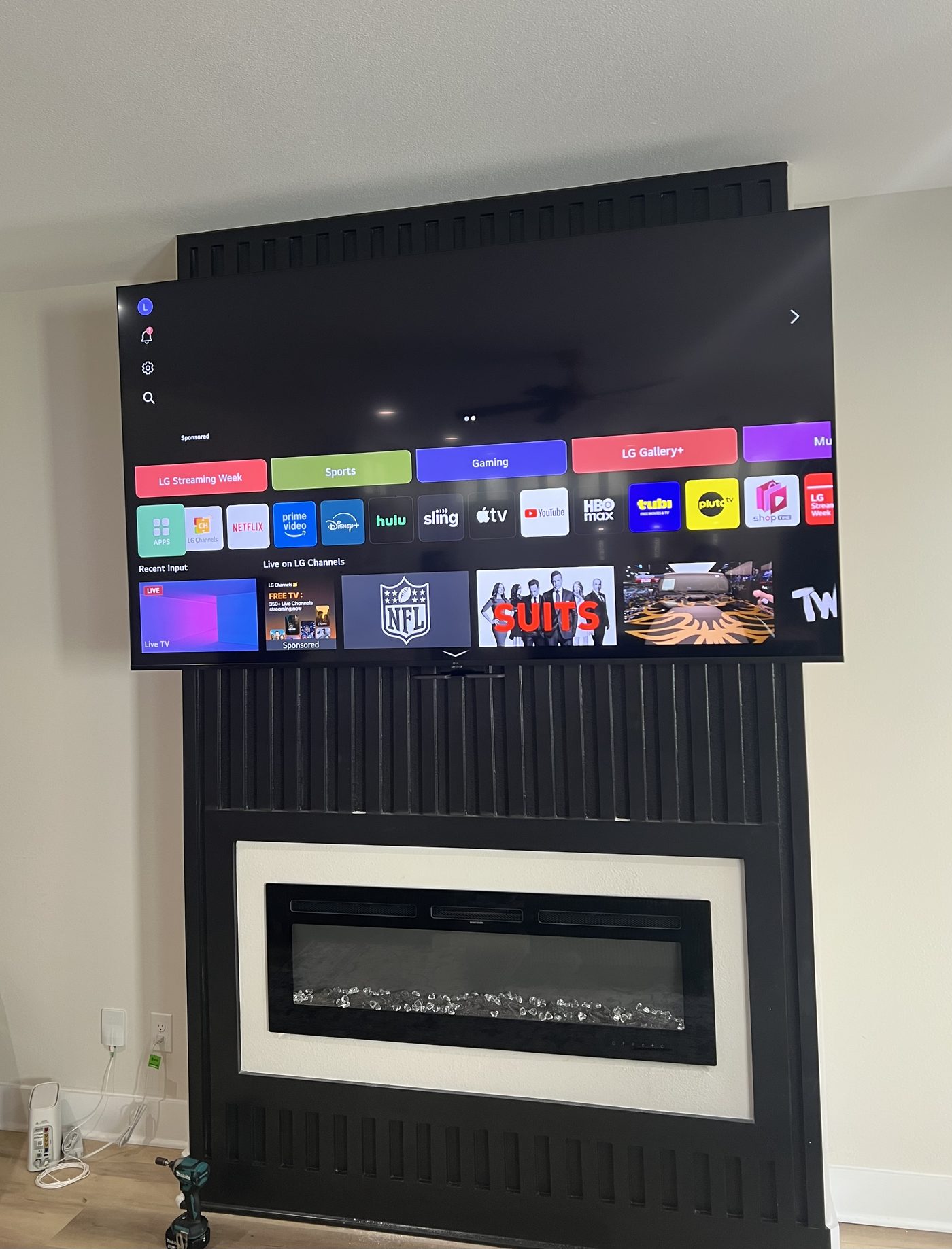 Large LG TV mounted above black electric fireplace fluted wall panel Dallas TX