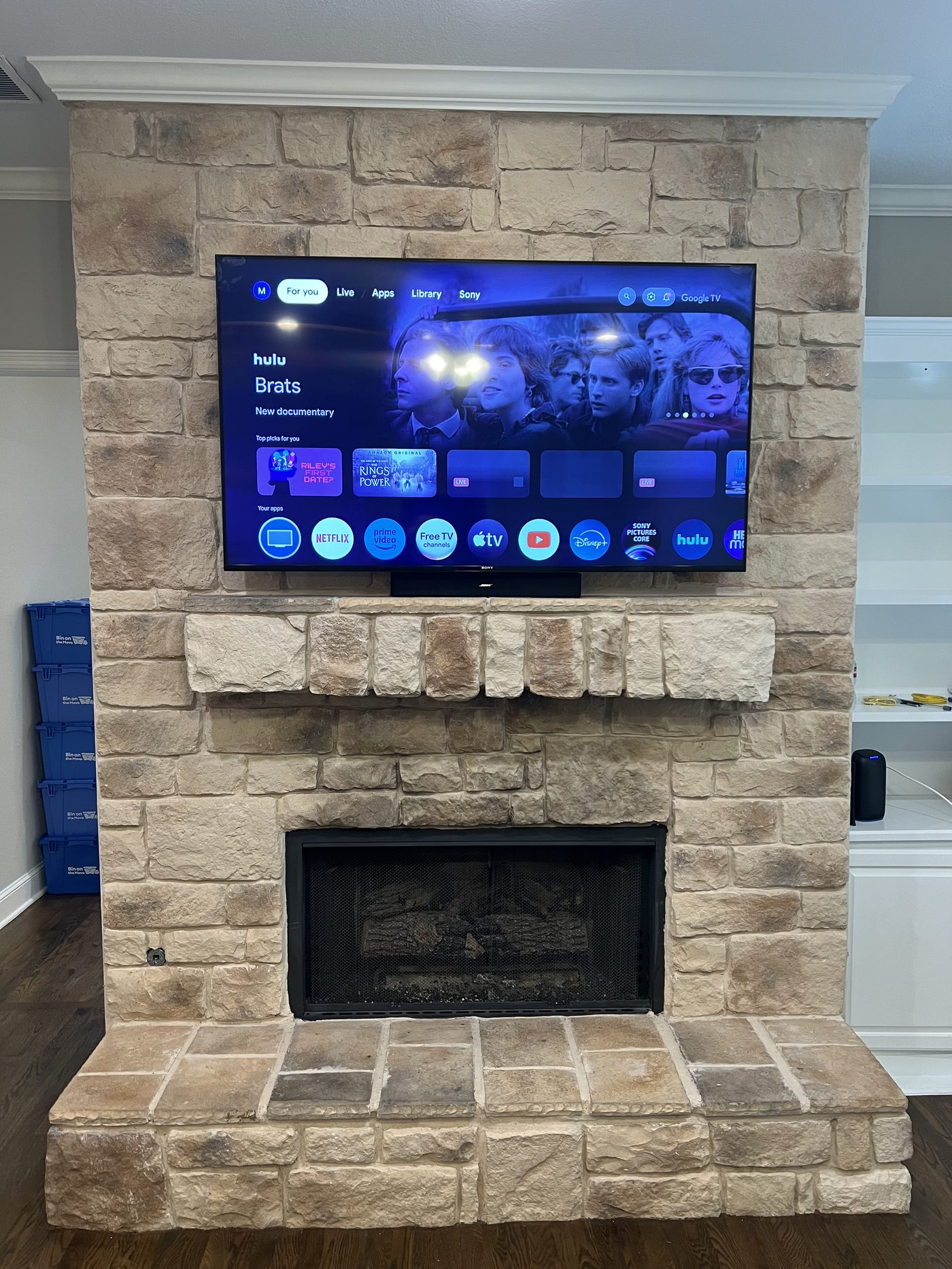 Sony TV mounted on natural stone fireplace with wood mantle Dallas TX