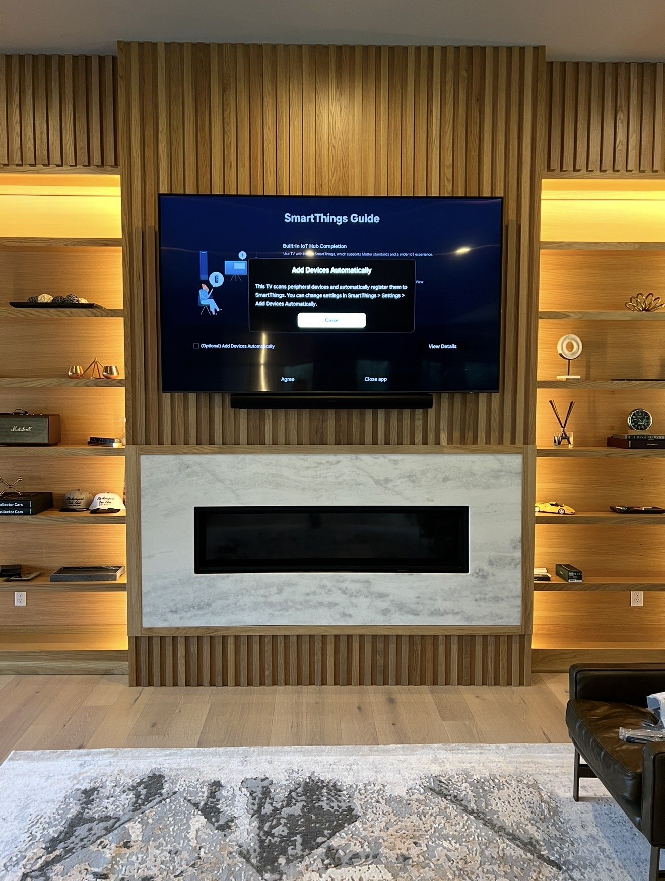 TV and soundbar mounted in luxury wood entertainment wall with built-in shelves above marble fireplace in Dallas TX - EZ TV Mounting